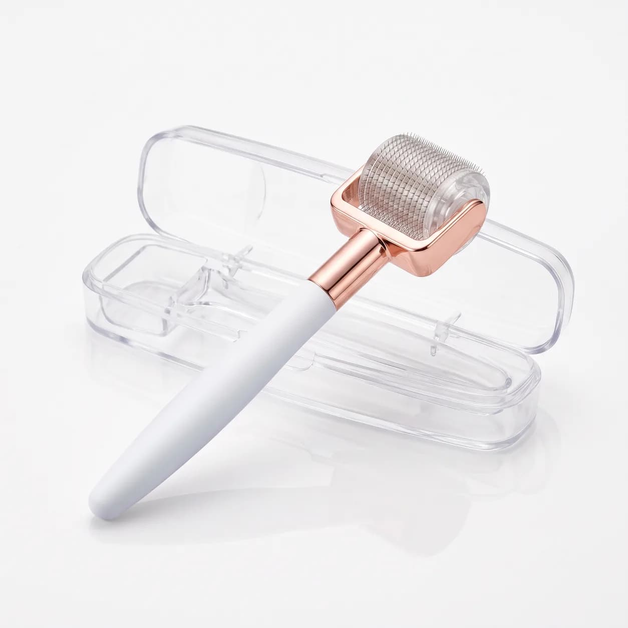 0.5mm derma roller with white handle and rose gold collar beside its clear storage case